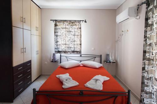 a bedroom with a red bed with white towels on it at Alexandros in Lefkada