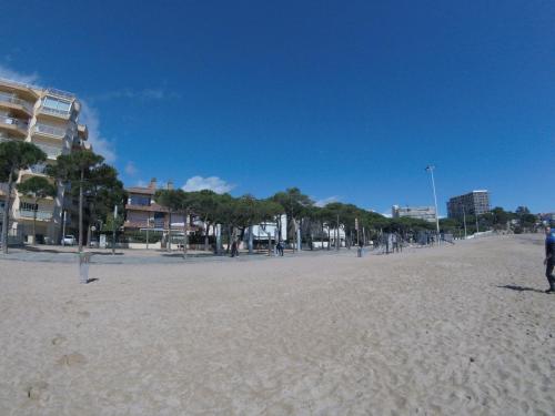 a sandy beach with trees and buildings in the background at Marina Mar in Platja  d'Aro