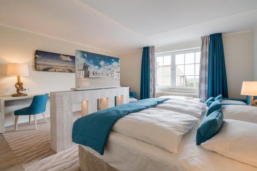 a bedroom with a large bed with blue curtains at Hotel Garni Kölfhamm in Sankt Peter-Ording