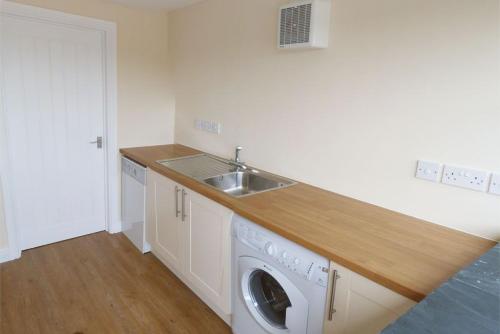 una cocina con fregadero y lavadora en Brynheulwen, en Llanilar