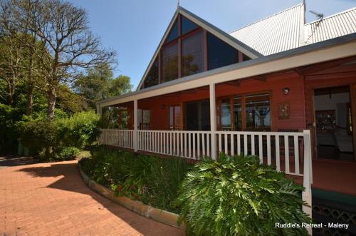a red house with a porch and a white fence at Ruddles Retreat in Maleny