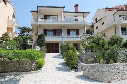 a house with a stone walkway in front of it at Apartments Vila Marica in Rabac
