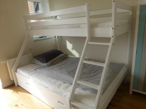 a bedroom with a white bunk bed with a ladder at Loft 270° im Kapitänshaus Wangerooge in Wangerooge