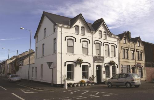 Biały budynek z samochodem zaparkowanym przed nim w obiekcie Seaview House Bed and Breakfast w mieście Larne