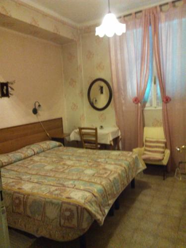 a bedroom with a bed and a table and a chair at Pensione Santachiara in Sanremo