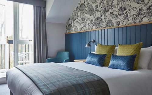 a bedroom with a large bed with blue and yellow pillows at The Bear Hotel by Greene King Inns in Hungerford