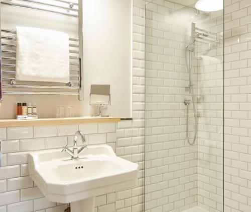 a white bathroom with a sink and a shower at The Bear Hotel by Greene King Inns in Hungerford