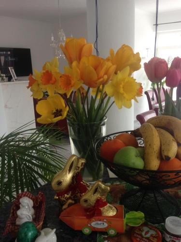 a table with a bowl of fruit and a vase of flowers at Gästehaus Tante Tienchen 7 Minuten zu Fuss zum Europa Park , plus kostenloses Parkplatzticket Rulantica ,alle unsere Suiten haben einen Balkon in Rust