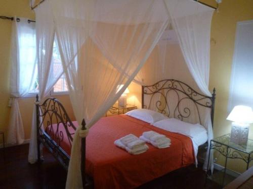 a bedroom with a canopy bed with towels on it at Villa Laurencin in Sainte-Rose