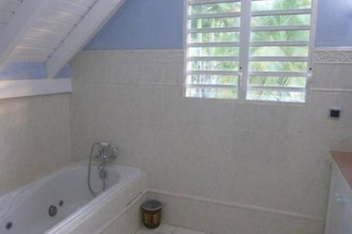 a white bathroom with a tub and a window at Villa Laurencin in Sainte-Rose