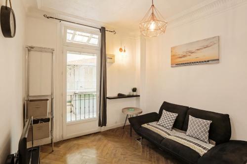 - un salon avec un canapé noir et une fenêtre dans l'établissement AMAZING 1 bedroom LOFT in NICE city centre seafront, à Nice