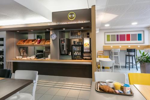 a breakfast counter in a restaurant with a tray of food at B&B HOTEL Toulouse Cité de l'Espace Mouchotte in Toulouse