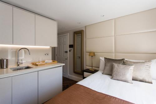 a bedroom with a white bed and a kitchen at Baker Street by Viridian Apartments in London
