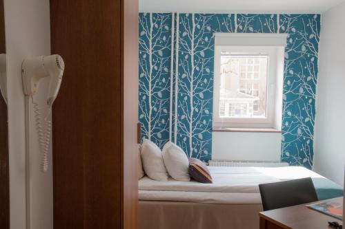 a small room with a bed and a window at Hotell Conrad in Karlskrona