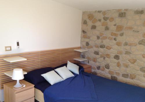 a bedroom with a blue bed and a stone wall at Il Caprarizzo in Palinuro