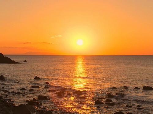 a sunset over the ocean with the sun setting at Pension Moon Villa in Onna