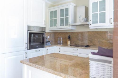 eine Küche mit weißen Schränken und einer Granitarbeitsplatte in der Unterkunft Villa Elena in Sevid