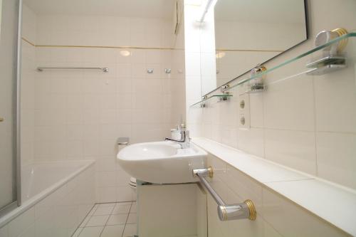 a white bathroom with a sink and a bath tub at FeWo Gudrun in Garmisch-Partenkirchen