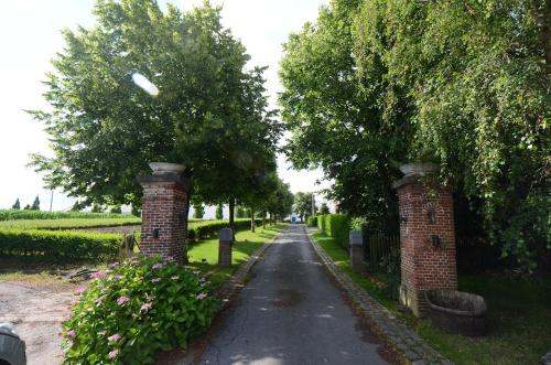 een straat met twee bakstenen pilaren en bomen bij Hotel het Elsland in Wervik