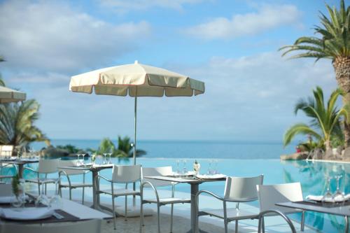 a restaurant with tables and chairs with the ocean in the background at Adrián Hoteles Roca Nivaria in Adeje
