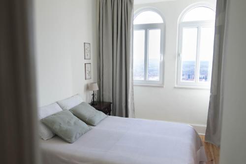 1 dormitorio con 1 cama blanca y 2 ventanas en Casa da Fonte Nova, en Lousã