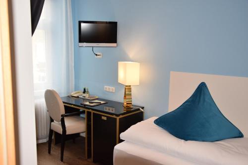 a room with a desk and a bed with a blue wall at Atel Hotel Lasserhof in Salzburg