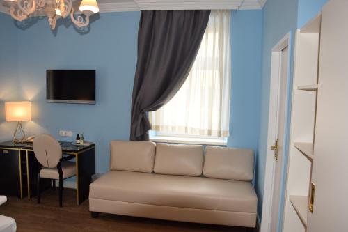 a living room with a couch and a desk and a window at Atel Hotel Lasserhof in Salzburg