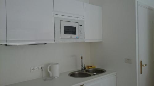 a white kitchen with a sink and a microwave at Monaco Studio "907" in Monte Carlo