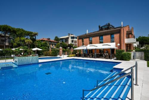 a large blue swimming pool in front of a building at DB Villas Le Ville del Lido Resort in Venice-Lido