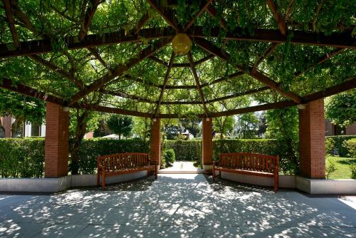 a pavilion with two benches in a park at DB Villas Le Ville del Lido Resort in Venice-Lido