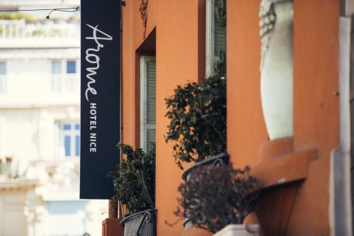 un panneau sur le côté d'un bâtiment avec des plantes en pot dans l'établissement Arome Hotel, à Nice