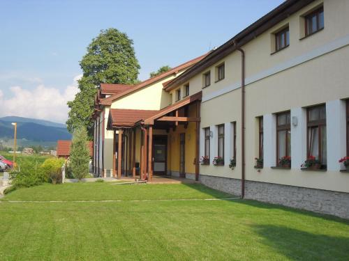 a building with a lawn in front of it at RED DEER Hotel in Brezno