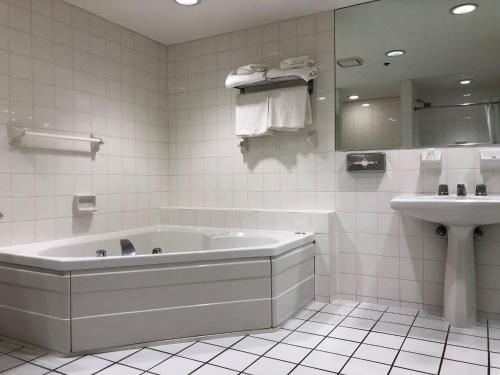 a white bathroom with a tub and a sink at Best Western Atlantic City Hotel in Atlantic City