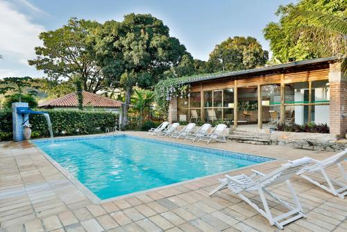 a swimming pool with chairs and a house at Solar dos Ipês in Serra do Cipo