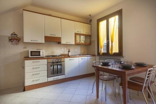 a kitchen with white cabinets and a wooden table at La Fonte degli Angeli Apartments in Suvereto