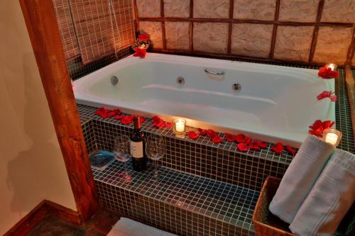 a bath tub with candles and red roses in a bathroom at Solar dos Ipês in Serra do Cipo