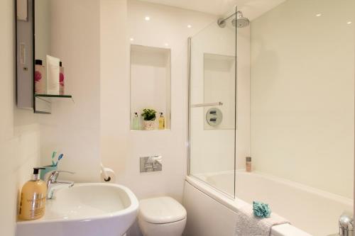 La salle de bains blanche est pourvue d'un lavabo, de toilettes et d'une douche. dans l'établissement Finchley Central - Luxury 2 bed ground floor apartment, à Hendon