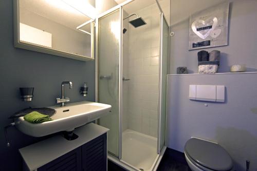 a bathroom with a sink and a shower and a toilet at Jac-Cosy in Fleurier