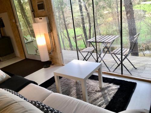 sala de estar con mesa de centro blanca frente a una ventana en Relax Container, en Aguiar da Beira