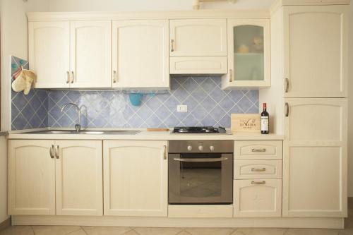 a kitchen with white cabinets and a sink and a stove at La Fonte degli Angeli Apartments in Suvereto