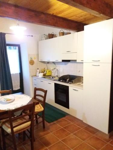 a kitchen with white cabinets and a table and a dining room at Il Nespolo in Modolo