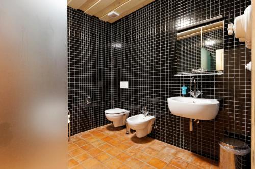 uma casa de banho com azulejos pretos, um lavatório e um WC. em Porčův mlýn em Býkovice