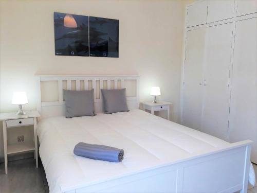 - un grand lit blanc avec un oreiller bleu dans l'établissement Mouramar- Garagem, Piscina & Wifi, à Vilamoura
