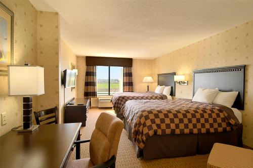 a hotel room with two beds and a desk at Wingate By Wyndham - Warner Robins in Warner Robins