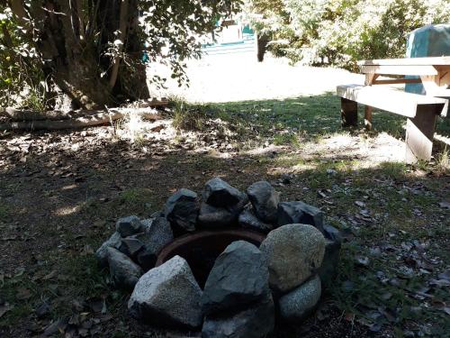 una pila de rocas en una hoguera junto a un banco en Cabaña Rincón de Manzano, en Villa La Angostura