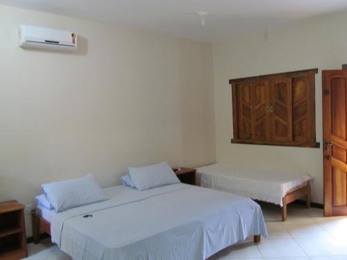 a bedroom with two beds and a cabinet at Pousada da Paz in Itacaré