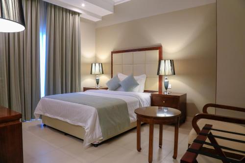 Muscat Inn Hotel في مسقط: غرفة فندقية بسرير كبير وكرسي