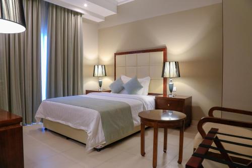 a hotel room with a large bed and a chair at Muscat Inn Hotel in Muscat