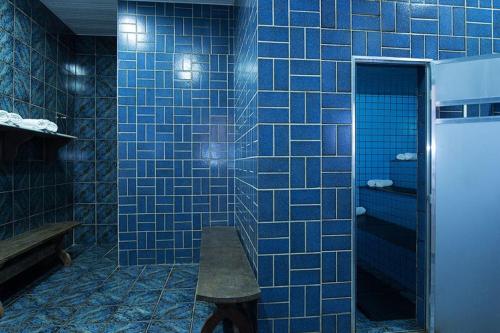 uma casa de banho em azulejos azuis com um banco em Hotel da Lea em Guarapari