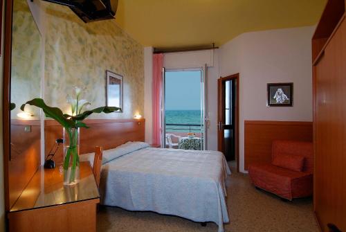 ein Schlafzimmer mit einem Bett und einer Vase aus Blumen auf einem Tisch in der Unterkunft Hotel Cristina in Senigallia
